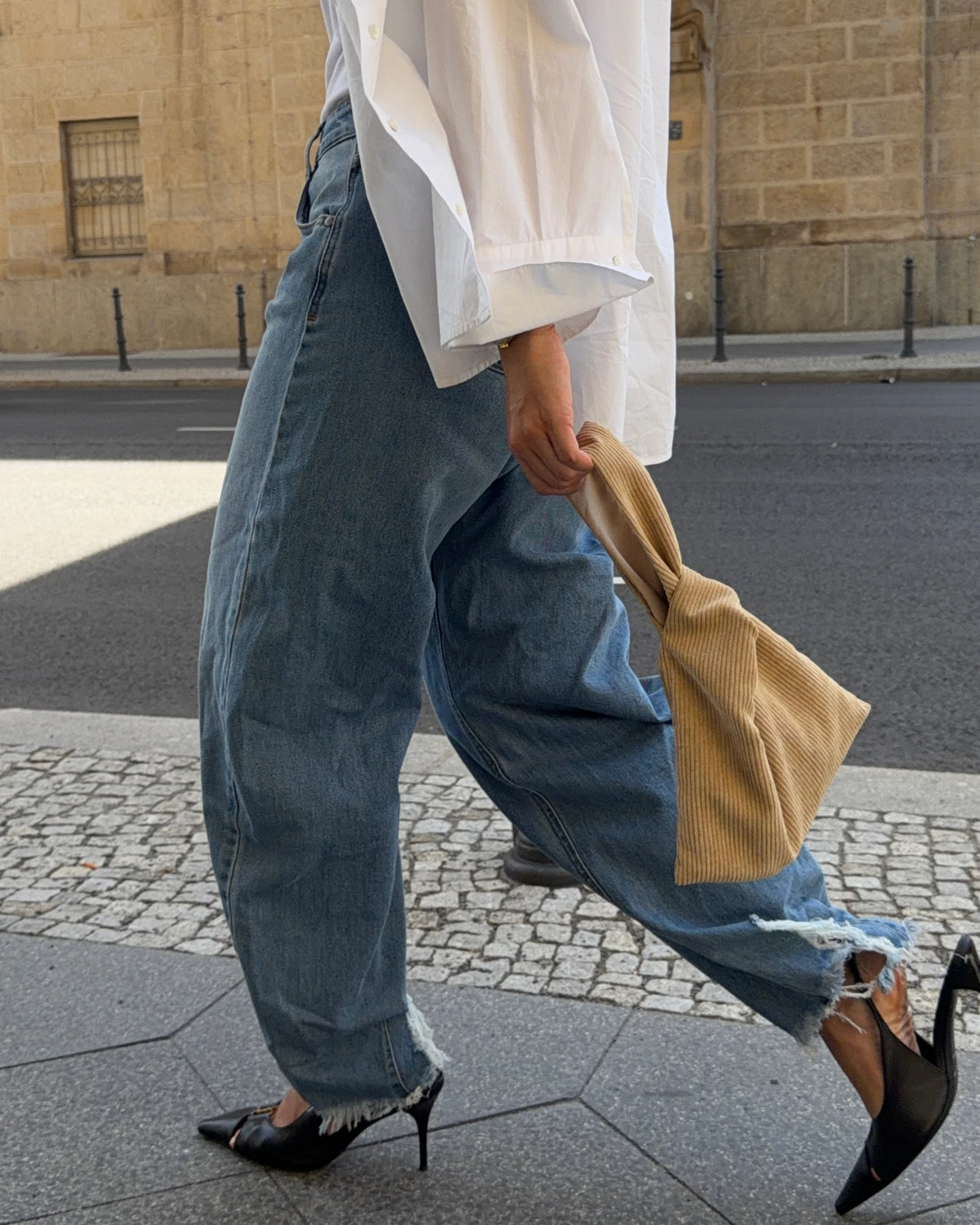 Beige corduroy Hazel Bag held at the side, styled with baggy jeans and heels